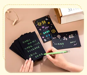 Detalle de escritura en tarjetas postales negras DIY con un rotulador verde metálico