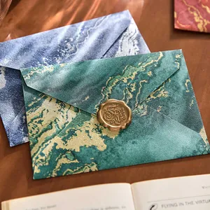Elegante sobre vintage con patrón de mármol, detalles dorados y sello de cera oro