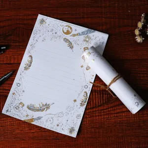 Elegante carta da lettere tema stelle con piume e penne in lamina d'oro e argento.