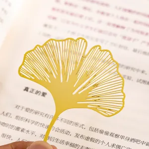Elegante segnalibro in metallo traforato a forma di foglia di ginkgo dorata su un libro.