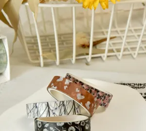 Close-up of four washi tape rolls with various elegant floral patterns for DIY scrapbooking.