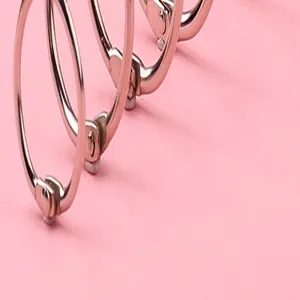 Dettaglio macro di anelli metallici per rilegatura su sfondo rosa