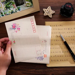 Vintage floral envelope and letter paper set on a wooden desk with pen