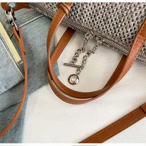 Detailed view of silver-tone metal chain and woven fabric on a brown leather handbag.