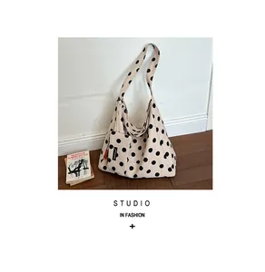 Detailed view of a large capacity cream canvas tote bag with stylish black polka dots