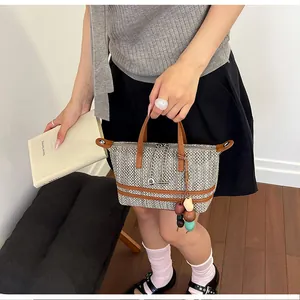 Detailed view of stylish grey hollow woven tote bag with brown handles held by a model