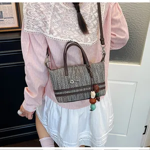 Chic hollow woven crossbody tote bag for women featuring a decorative bead charm