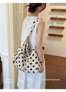 Detailed view of a large capacity polka dot canvas shoulder bag on a model in a studio