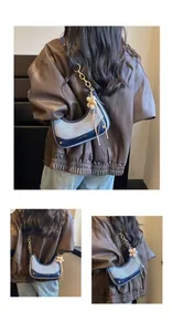 Chic blue hobo bag with gold chain strap and flower charm on model