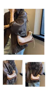 Detailed close-up of a stylish crescent shoulder bag with chain strap and flower charm
