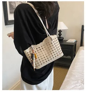 Gedetailleerd overzicht van een beige zomerse geweven tote bag met kralenhanger.