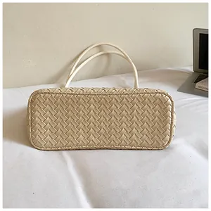 Detailweergave van de onderkant van een beige geweven draagtas met fijn vakmanschap