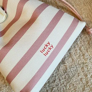 Nahaufnahme einer rosa-weiß gestreiften Kordelzug-Beuteltasche mit lucky lucky Aufdruck