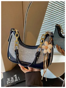 Detailed view of the navy color-block hobo bag with gold chain and flower charm