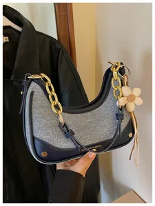 Detail view of chic contrast hobo bag with chunky gold chain strap and floral charm