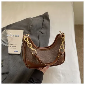 Close-up of brown textured hobo bag with gold chain strap and sleek contrast design.
