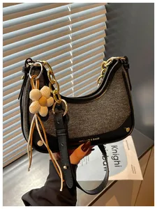Chic denim and leather hobo bag with decorative gold chain and cute flower charm accessory
