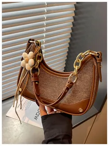 Detailed view of elegant brown textured crescent handbag with gold chain strap