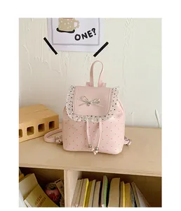 Sweet pink polka dot mini backpack with lace ruffles and bow detail on a shelf