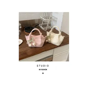 Detailansicht von rosa und cremefarbenen Handtaschen mit Blumen- und Perlenanhängern.