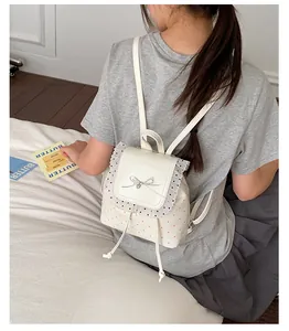 Sweet white lace trim mini backpack with red polka dots worn by a girl in detail view