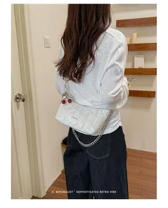 White quilted chain shoulder bag with cherry charm shown on a model from behind