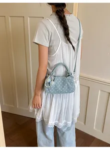 Close-up detail of a light blue polka dot handbag styled with a feminine outfit