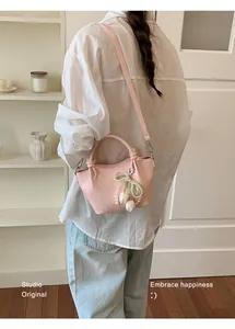 Elegante rosa Eimertasche mit Perlen-Tulpen-Anhänger, getragen von einem Modell im Lifestyle.