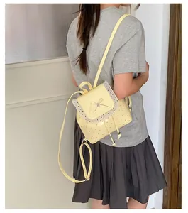 Rear view of a sweet yellow girl's backpack featuring delicate lace trim and bow detail