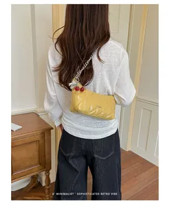 Back view detail of a stylish yellow quilted chain shoulder bag with cherry charms