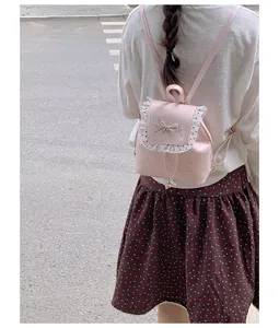 Sweet pink mini backpack with lace trim and bow worn by model in casual setting