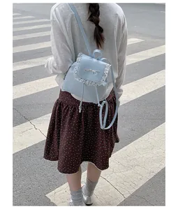 Back view of a sweet light blue lace backpack with bow detail styled with a polka-dot skirt