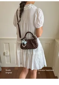 Brown polka dot handbag with pearl charm shown in a chic outfit context.
