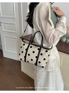 Elegante bolso tote de lona con lunares mostrado como bolso de hombro de mujer estilo vintage.