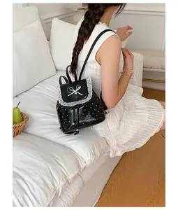 Sweet black polka dot backpack with white lace trim worn by a model in a white dress