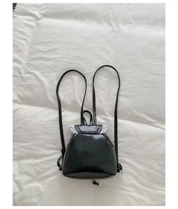 Detailed macro view of a black sweet lace trim backpack with thin straps on white bed.