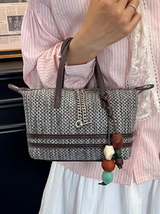 Chic brown woven hollow handbag with colorful bead tassel charm held by a model