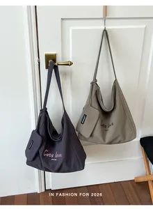 Close-up detail of large capacity canvas tote bags in gray and khaki colors hanging on a door