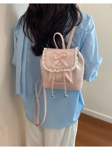 Exquisiter rosa Mini-Rucksack mit Perlenherz und Spitze auf dem Rücken des Models.