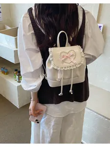 Detailansicht eines cremefarbenen Mini-Rucksacks mit Spitzenbesatz und Perlenherz