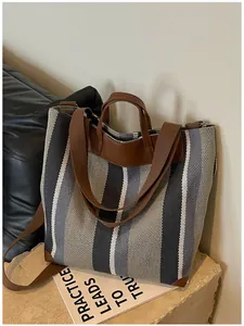 Vue détaillée d'un sac cabas en toile rayée avec poignées en similicuir marron.