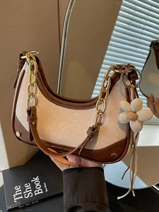 Elegant women's crescent shoulder bag with gold chain strap and floral charm pendant