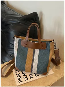Grand sac cabas en tissu rayé avec poignées en cuir marron sur livre d'accessoires