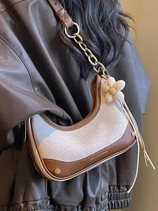 Stylish two-tone crescent shoulder bag with gold chain strap and flower charm accessory