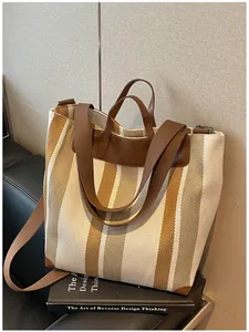 Détail d'un grand sac cabas en toile à rayures avec poignées en cuir marron