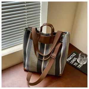 Sac cabas en toile rayée à la mode avec lanières en cuir sur une table en bois près d'une fenêtre