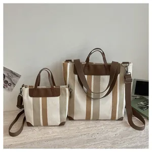 Détail de grands et petits sacs cabas en toile rayée avec d'élégantes anses en cuir brun
