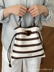 Stilvolle braun-weiß gestreifte Beuteltasche mit Kordelzug und Schildpattverschluss.
