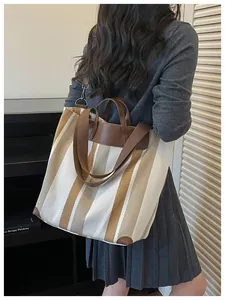 Détail lifestyle d'un sac cabas en toile rayée porté par un mannequin en extérieur