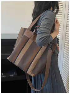 Vue détaillée d'un grand sac cabas en toile à rayures porté à l'épaule par un mannequin